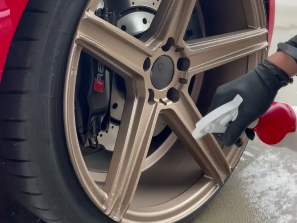Bronzefarbene Felge eines roten Audi R8 bei der Reinigung