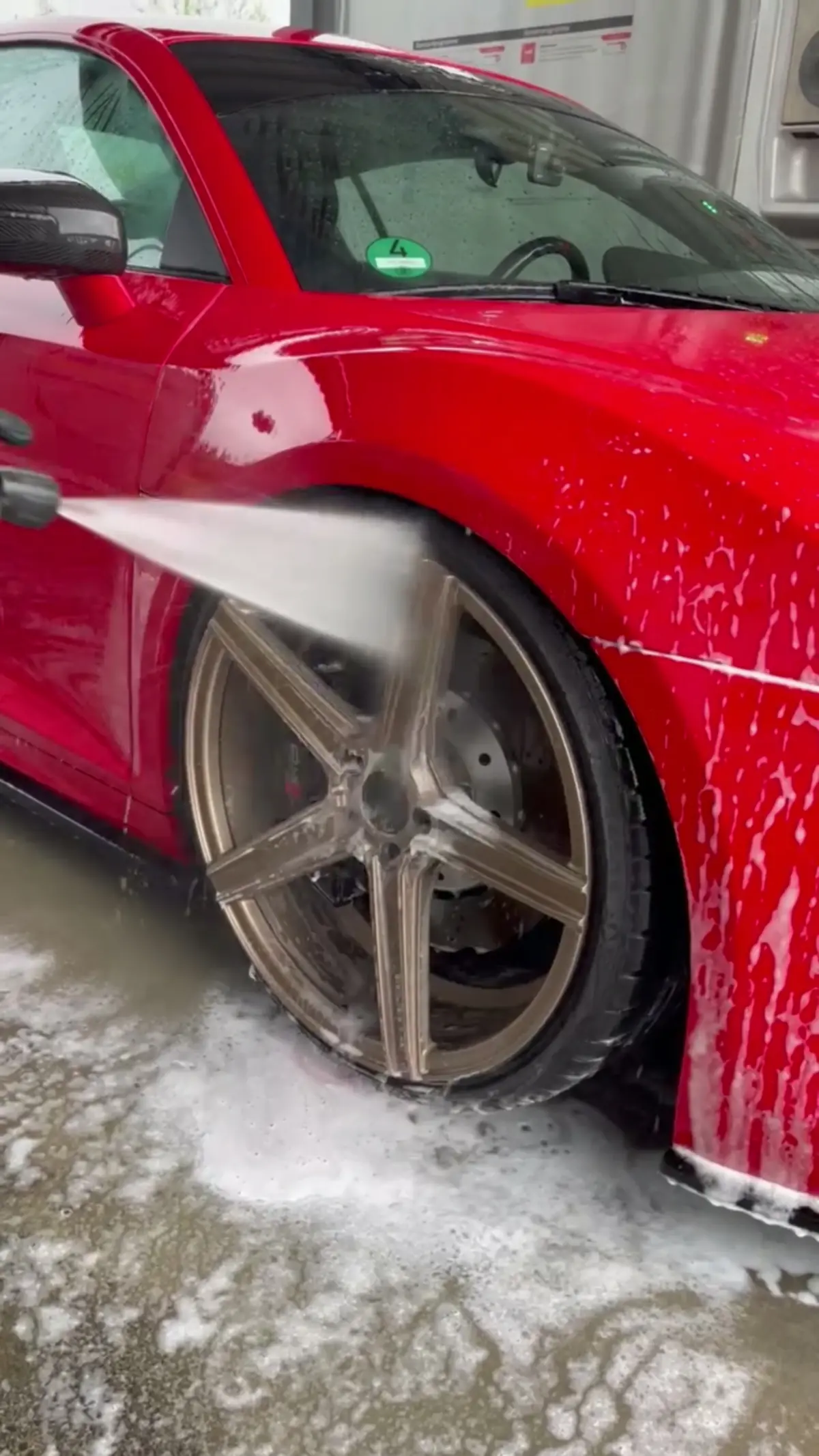 Felge eines roten Audi R8 wird mit dem Hochdruckreiniger abgespült