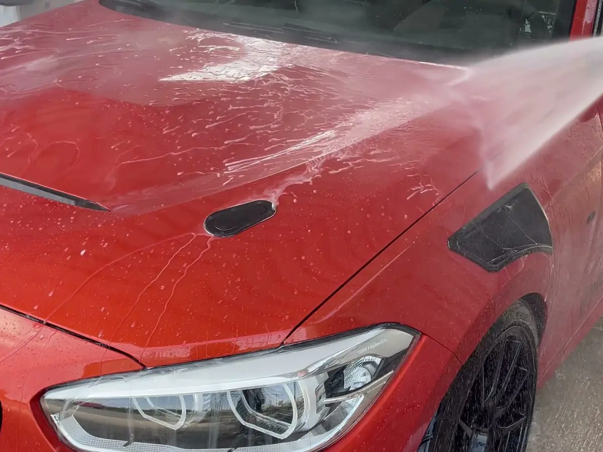 Ein BMW 140 wird bei der Autowäsche mit Wasser abgespült