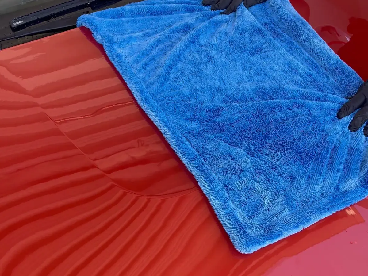 Mikrofasertuch auf der nassen Motorhaube eines keramikversiegelten BMW 140