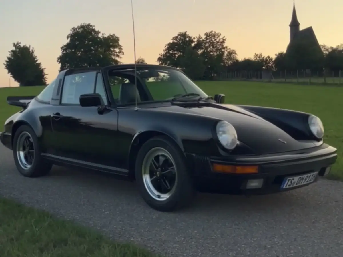 Schwarzer Porsche 911 auf einem Feldweg im Abendlicht