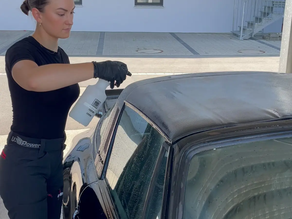 Das Dach eines schwarzen Porsche 911 Targa wird mit einem Sprühmittel behandelt