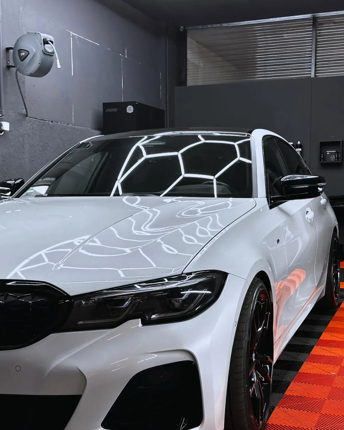 Weißer BMW unter dem Hexagon-Licht in der Werkstatt von Mad Cat Detailing