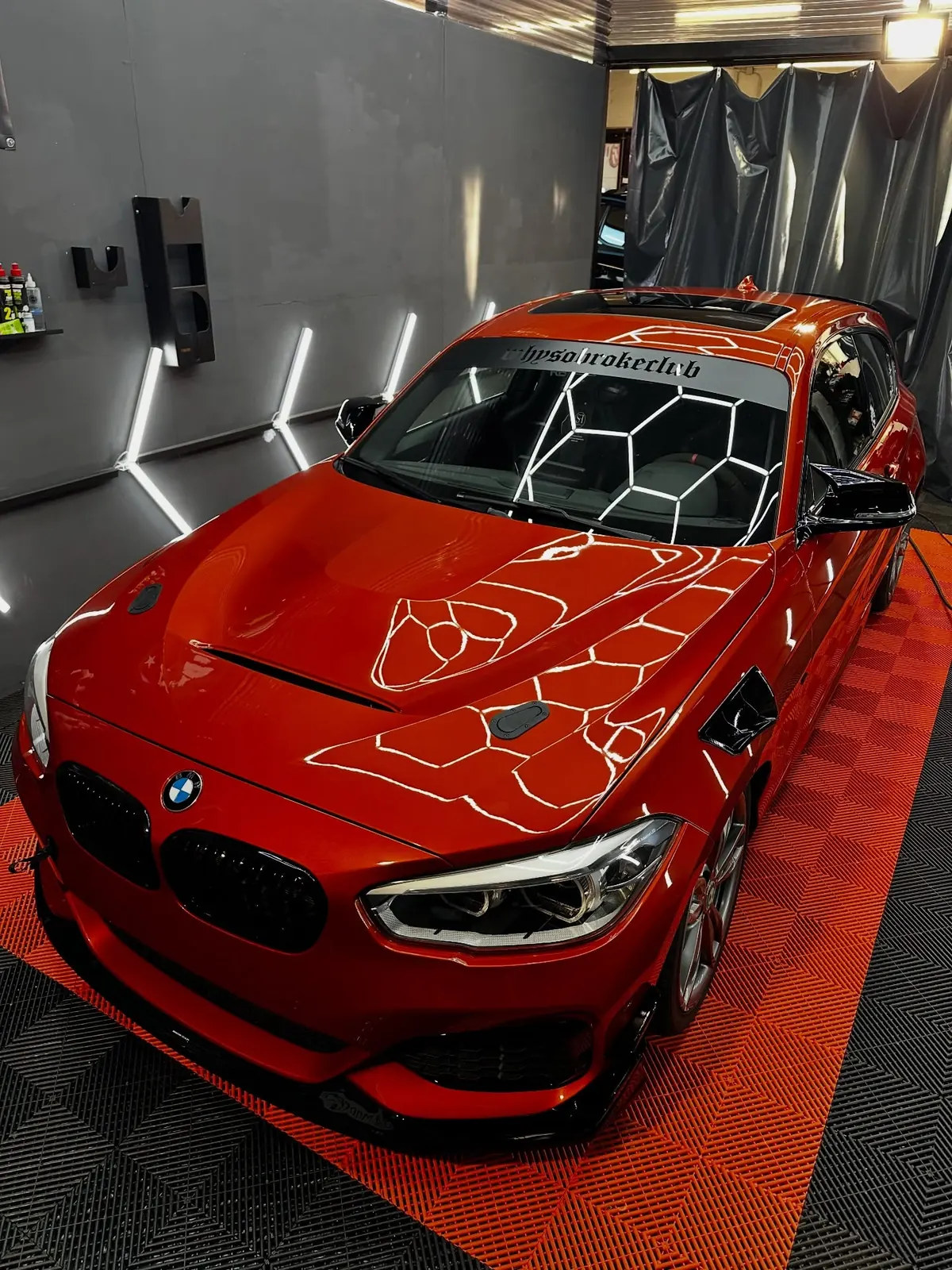 Roter BMW 140 unter dem Hexagon-Licht in der Werkstatt von Mad Cat Detailing