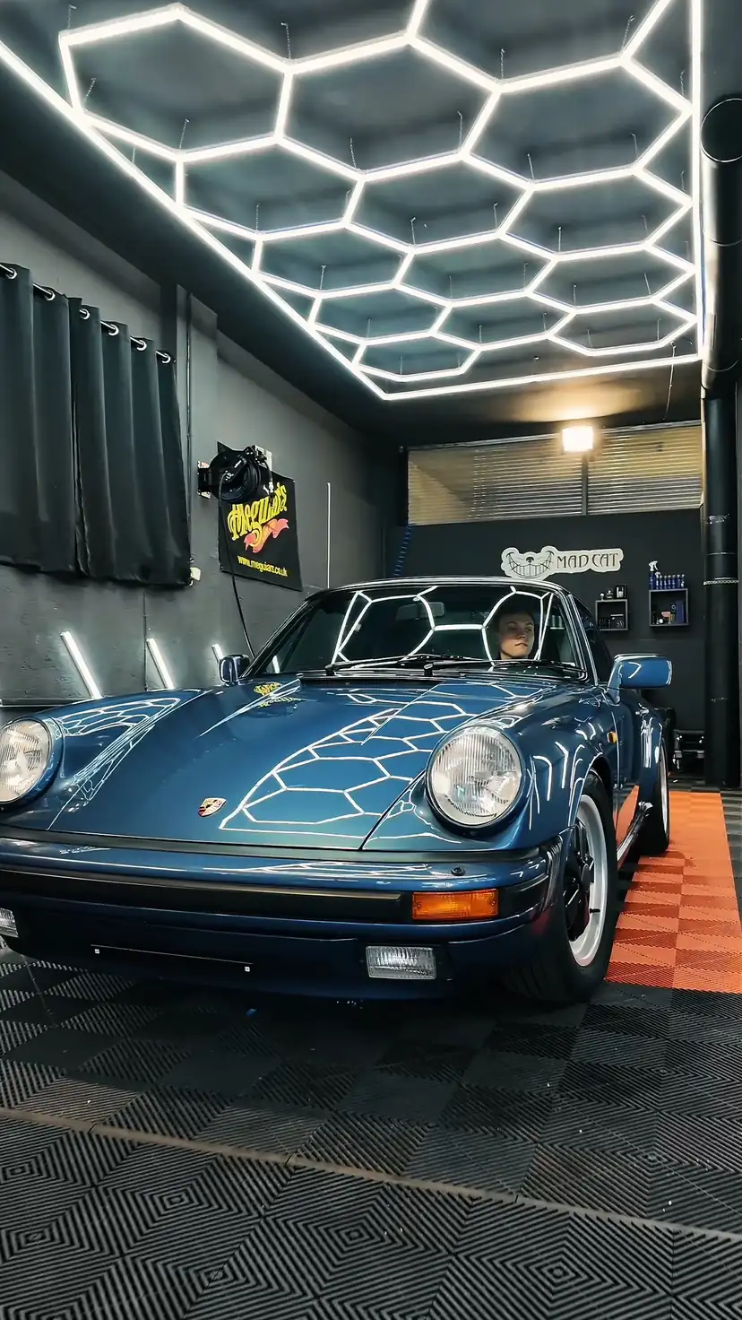 Blauer Porsche 911 Targa unter dem Hexagon-Licht in der Werkstatt von Mad Cat Detailing in Palling